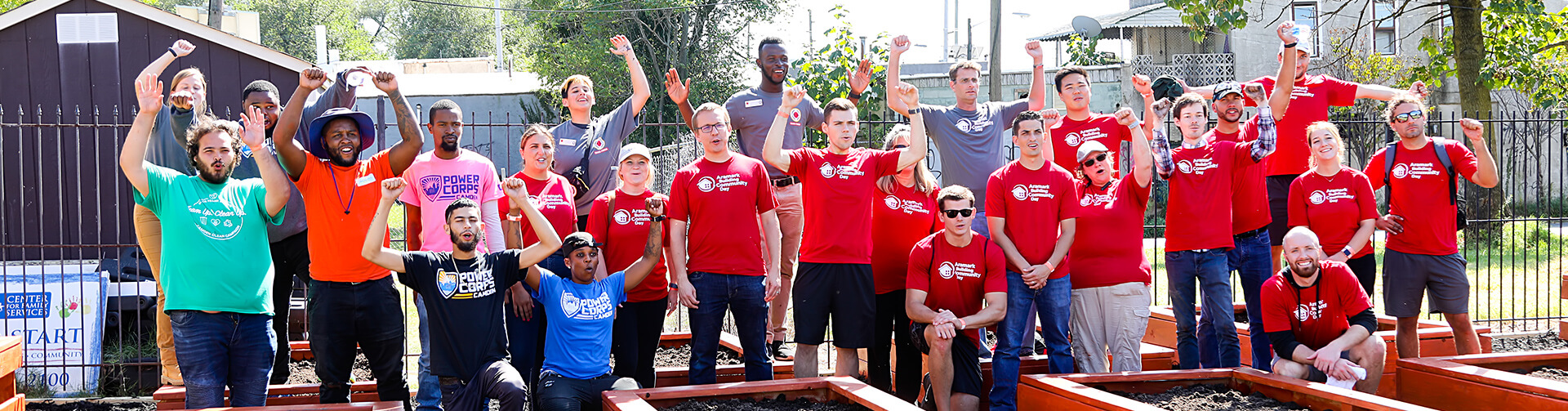 A group of volunteers celebrating inside a community garden.